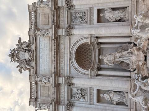 The ornate Trevi Fountain in Rome is captured in soft evening light, rich in marble detail.