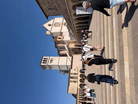 Tourists walk toward the Basilica of St Francis in Assisi on a sunny day.