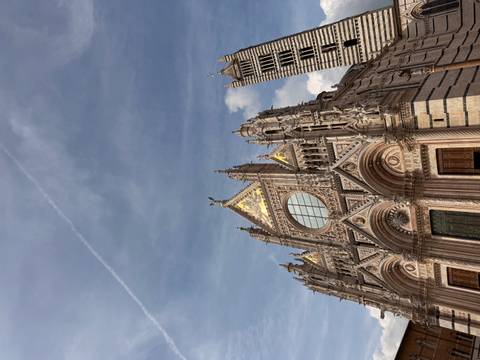 The ornate façade of Siena Cathedral rises into a blue sky with golden mosaics catching the light.