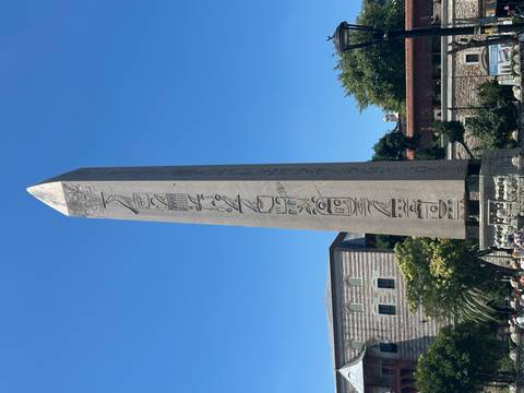 Tall ancient Egyptian obelisk with hieroglyphs standing in Istanbul's Hippodrome under clear blue sky.