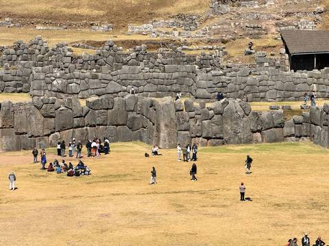 Groups relax on the grassy esplanade beneath the massive zig-zag walls of Sacsayhuamán fortress.