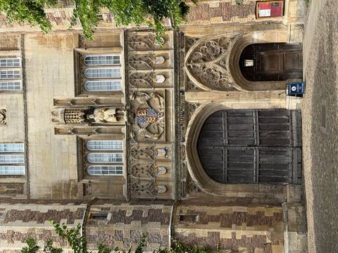 Historic stone gateway of a Cambridge college with ornate coats of arms and carved figures.