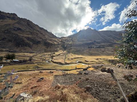 Golden valley landscape with village fields beneath towering Andean peaks.