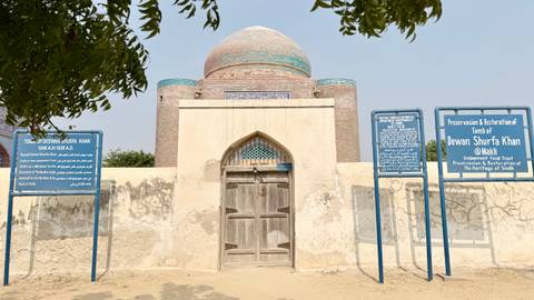 Restored tomb of Dewan Shurfa Khan with informational boards outside.