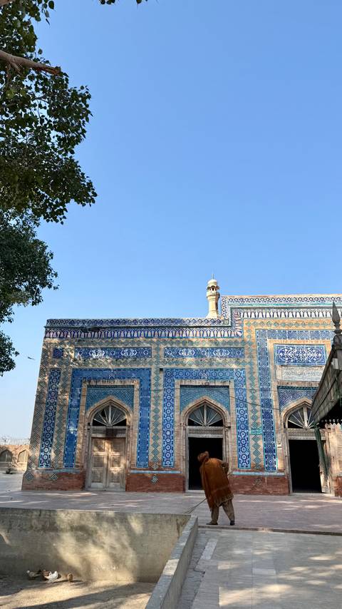 Blue-tile patterned wall and minaret tip of historic Pakistani mosque against sky.