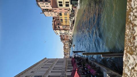 View down the Grand Canal in Venice with colorful buildings, awnings and boats navigating the waterway.