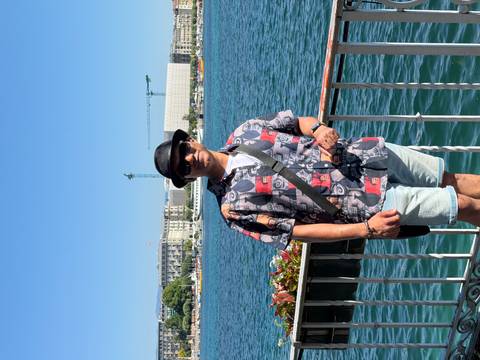 Full-body portrait of a traveller by the Geneva lakeside railing on a bright summer day.