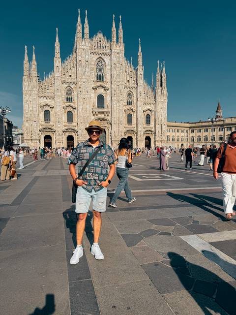 Traveller standing in Milan’s Piazza del Duomo with the cathedral façade and crowds around.