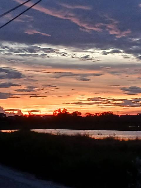 Blurry image of an orange and pink sunset over water with dark cloud formations.