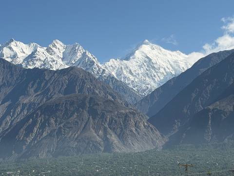 Snow-capped mountain peaks towering above dark rocky ridges under clear blue sky