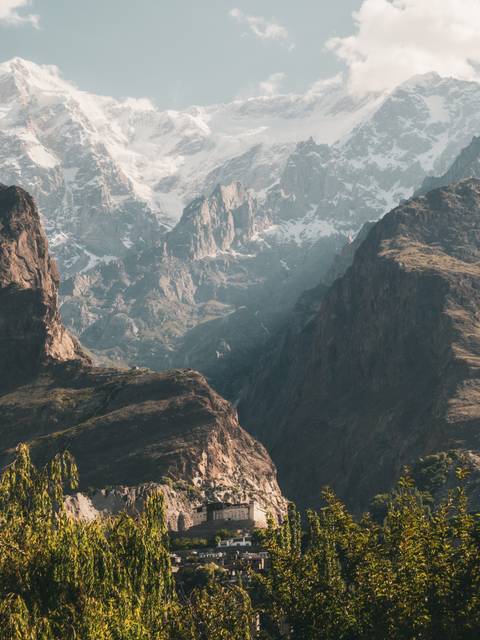 Layered mountain ridges with patches of snow and a deep, hazy gorge below.
