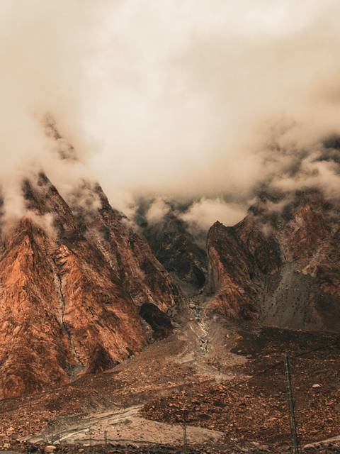 Rust-hued rocky peaks disappearing into low misty clouds.