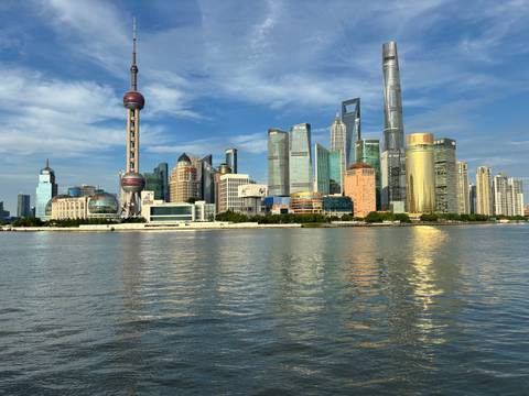 Iconic Shanghai skyline with Oriental Pearl Tower and glass skyscrapers reflected in the Huangpu River.