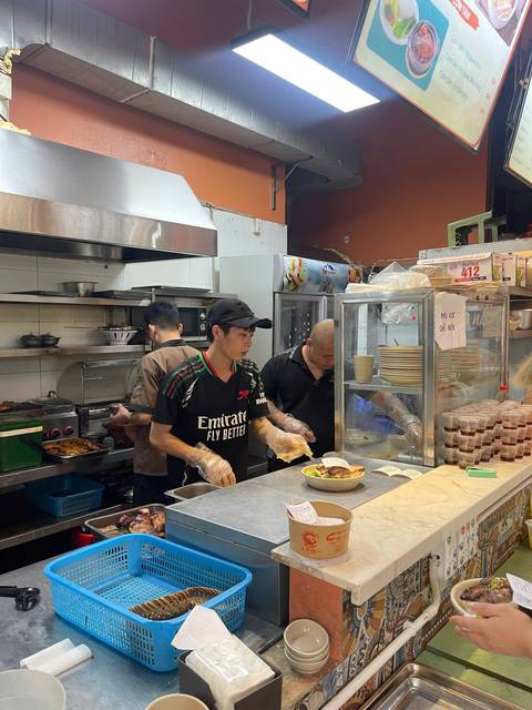 Busy Vietnamese street-food kitchen where cooks prepare dishes behind a glass counter.