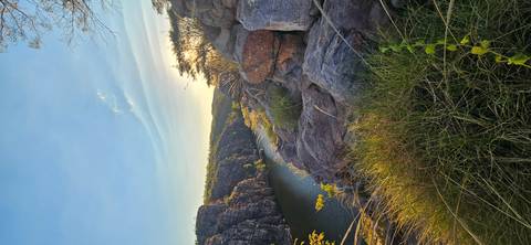 Rocky gorge framed by cliffs and vegetation with a tranquil river flowing below under warm afternoon light