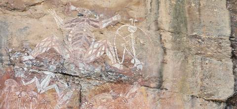 Ancient Aboriginal rock art depicting animals and human figures painted on a sandstone wall