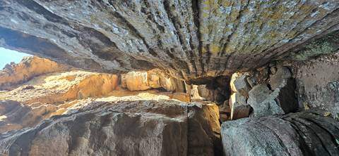 Narrow sandstone passageway with layered rock walls and scattered boulders