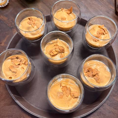Close-up overhead view of several double-walled glasses filled with creamy Vietnamese egg coffee topped with crunchy flakes.