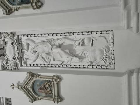 Elaborate white bas-relief sculpture inside ornate church interior.