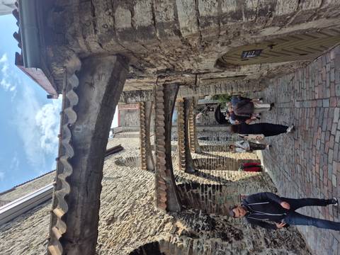 Narrow medieval lane in Tallinn with stone arches and tourists walking.