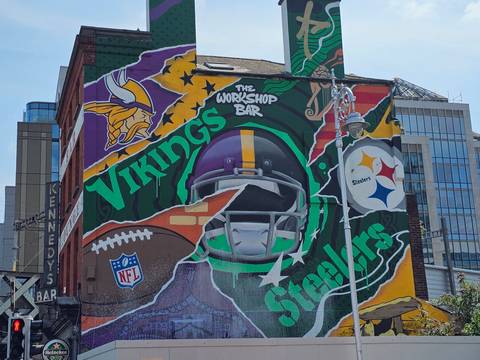 Colourful sports themed street mural featuring NFL helmets on a city building