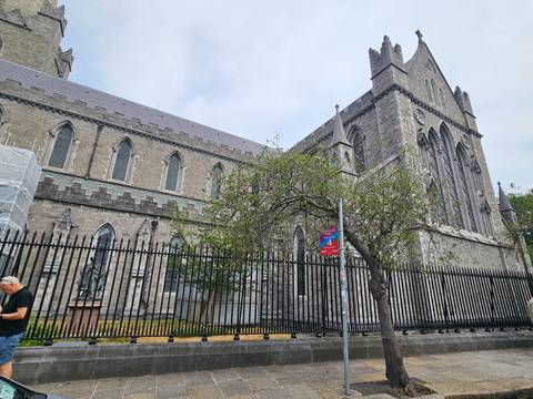 Exterior of St Patrick’s Cathedral Dublin behind black iron railings and leafy tree