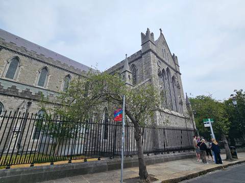Angled exterior shot of St Patrick’s Cathedral Dublin with iron fence and tourists at corner