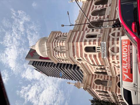 Historic Mughal-style National Textile Museum contrasted against a modern skyscraper under a bright blue sky in Kuala Lumpur.