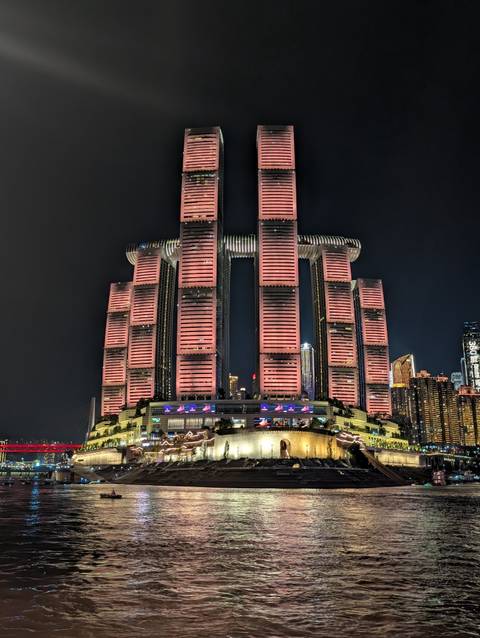 Night view of Chongqing’s futuristic Raffles City skyscrapers bathed in pink lighting against the dark sky.