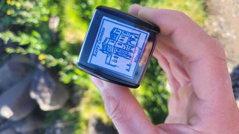 Close-up of a hand holding a Kerry Camino pilgrim stamp against a grassy backdrop.