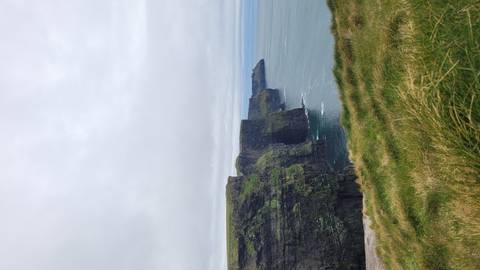 Dramatic sheer cliffs plunge into the Atlantic Ocean under a grey sky at the Cliffs of Moher.