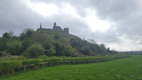 Rock of Cashel rising on a green hill beneath a cloudy grey sky.