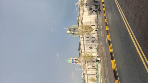 Neoclassical Custom House with green dome along riverside road after rainfall, rainbow light on facade.