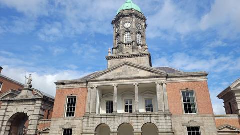 Clock-towered Georgian courtyard of Dublin Castle against a vivid blue sky.