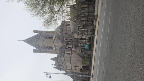 Street-level view of Christ Church Cathedral with misty grey sky across an empty road.