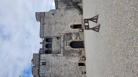 Stone courtyard and high keep walls of a medieval castle with a wooden stocks display.