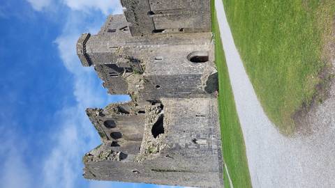 Ruined grey stone walls and towers of the Rock of Cashel beneath a vivid blue sky.