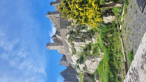 View up limestone outcrop toward the Rock of Cashel’s defensive walls against a deep blue sky.