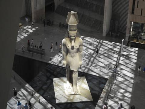 Colossal statue of Ramses II in modern museum atrium lit by patterned skylight