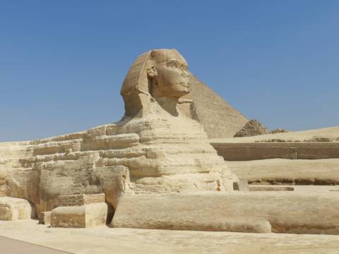 Great Sphinx of Giza with pyramid backdrop under cloudless blue sky