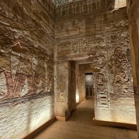 Ancient corridor with raised relief carvings and faded pigments inside Egyptian tomb