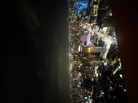 Sweeping nighttime skyline of a modern city with illuminated towers and busy streets below.