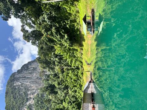 Turquoise lake mirrors towering limestone cliffs and floating wooden bungalows backed by dense rainforest.