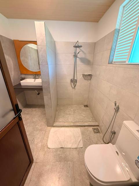Modern hotel bathroom with walk-in shower, handheld showerhead and neutral tile finish.