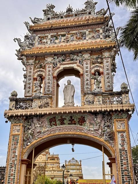 Close-up of a richly decorated pagoda tower featuring a white Buddha statue framed by intricate mosaics.