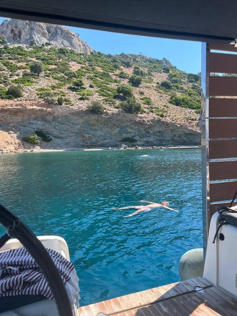 Person floating on their back in clear turquoise cove surrounded by rocky coast.