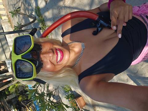 Close-up selfie of a smiling woman wearing a snorkel mask and tube, ready for underwater adventure.