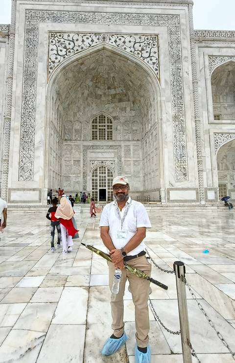 A tourist stands in front of an intricately carved marble doorway inside the Taj Mahal complex.