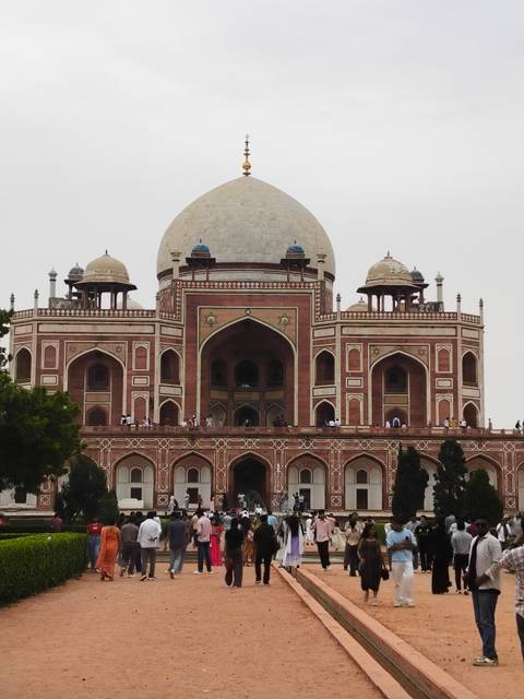 Humayun's Tomb stands majestically with its domes and arches framed against a pale sky.