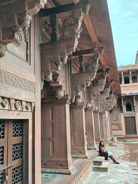Close-up of intricately carved red-sandstone pillars and brackets in a Mughal palace.